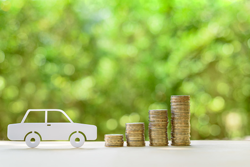 Used and second hand vehicle / car or auto loan, financial concept : Sedan car and rows of coins on a table, depicts money loan or borrowing fund to buy a new or old car for personal or individual use
